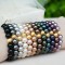 Pearl Stretch Bracelets shown in (left to right) Mystic Black, Dark Gray, White, Powder Almond, Bronze, Brown, Dark Green, Tahitian Look, Dark Purple, Burgundy, Mauve.